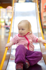 adorable baby sliding down on playground in mall