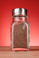Glass  pepper shakers  on red background