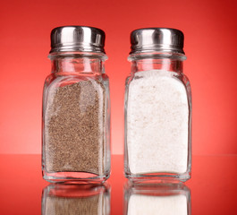 Glass salt and pepper shakers  on red background