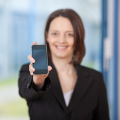 frau im büro zeigt handy display