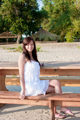 a young beautiful woman sits on a bench in a park