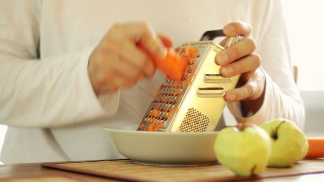 Man grating carrot on grater and eating carrot, steadicam shot