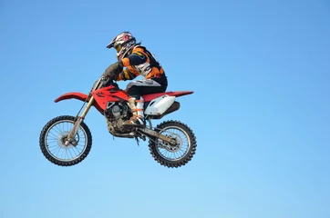 Fototapeten motocross rider jump, blue sky © VVKSAM