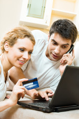 Couple with laptop, paying by credit card, at home