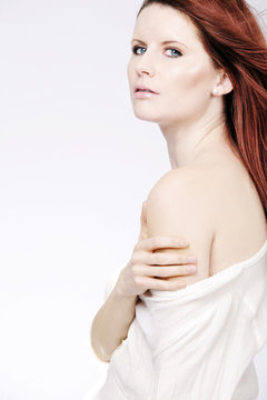 Girl with long red hair posing in the studio.