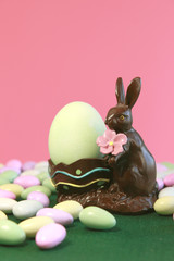 Chocolate Easter bunny holding egg with pastel candy