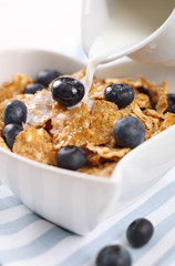 milk pouring into cereal with fresh blueberries