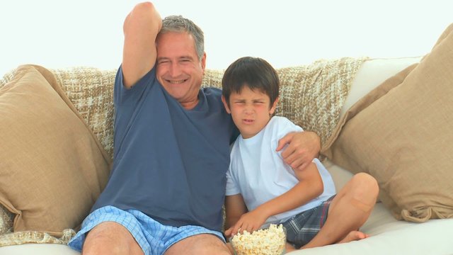 Mature man and his grandson watching a match on tv