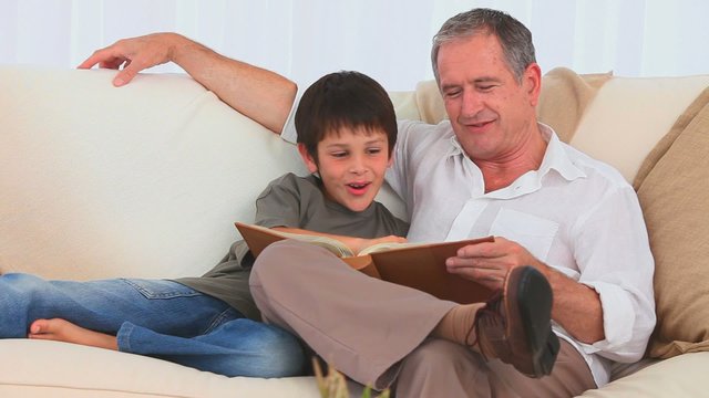 Boy looking at an album with his grandfather