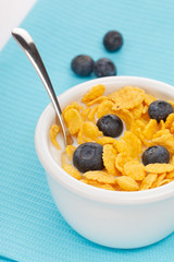 bowl of cornflakes with milk and blueberries