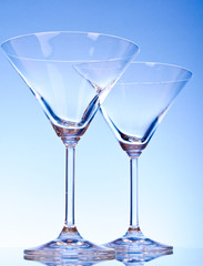 Two empty glasses of martini on the light blue background