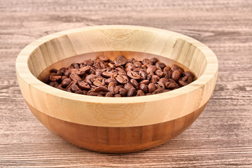 Plate with coffee beans on wooden table
