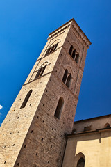 Medieval church bell tower over blue sky, Tuscany, Italy.