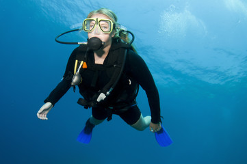 blonde scuba diver swims in clear blue water