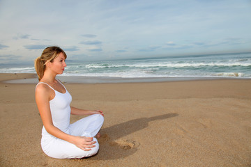 Beautiful blond woman doing stretching exercises on the beach