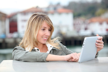 Beautiful blond woman using electronic tablet in town