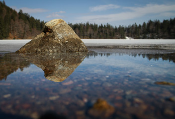 rock reflecting in lake