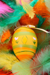Easter egg on pink and orange and green feathers.