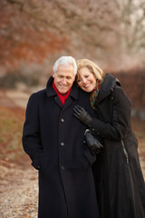 Senior Couple On Winter Walk Through Frosty Landscape