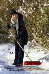 Woman sweeping pavement in winter