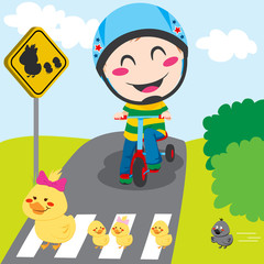 Boy on tricycle waiting in front of a ducks crossing sign