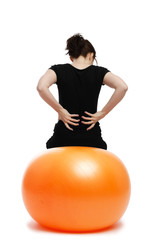 junge frau mit rückenschmerzen sitzt auf einem gymnastikball