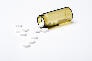 Pills and container on white background