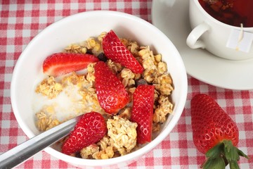 Breakfast cereal with strawberries and a cup of tea