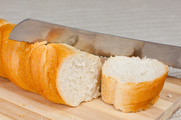bread and a slice on a wooden breadboard with a bread knife.