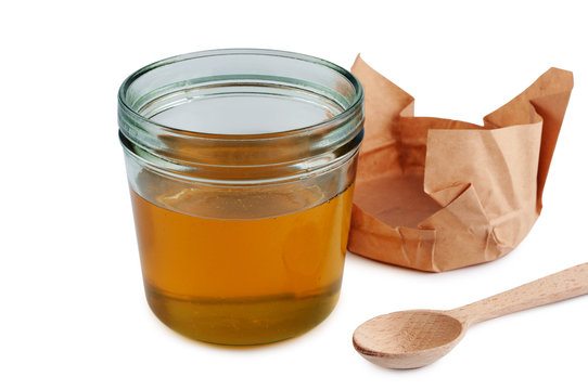 Honey in jar with wooden spoon. Close up isolated.