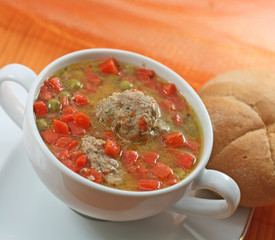 Home-made meatballs and vegetable soup, in a white soup cup