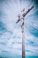 wooden cross with Jesus Christ and clouds with sun rays