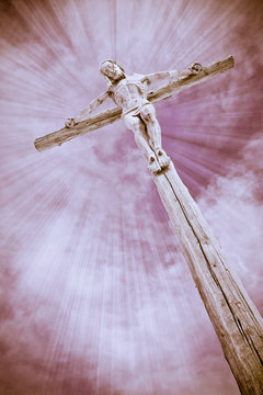 wooden cross with Jesus Christ and clouds with sun rays