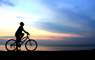 Fototapeta na wymiar Sylwetka człowieka jazda na rowerze z pięknym jeziorem w pobliżu