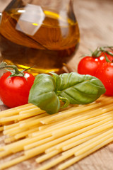 pasta, olive oil and tomatoes on the wood background