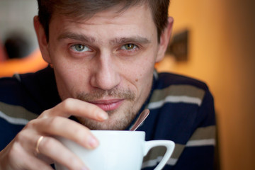Closeup portrait of a happy young man having a cup of tea