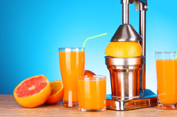 Juicer and oranges on blue background