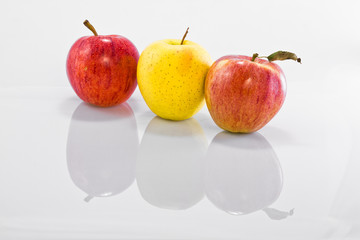 tre mele in fila su sfondo bianco lucido