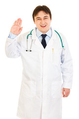 Smiling doctor showing salutation gesture isolated on white.