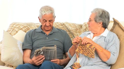 Woman knitting while her husband is reading the newspaper - Powered by Adobe