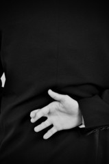 a businessman crosses his fingers behind his back