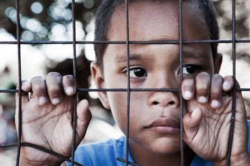 Asian boy against fence - sad expression looking to side