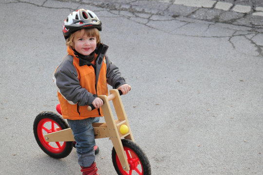 Kleiner Junge mit Helm auf dem Laufrad