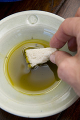 hand dipping bread in olive oil