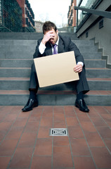 Depressed businessman holding blank cardboard