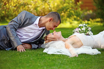 Naklejka na ściany i meble Portrait of happy newlyweds on grass in park