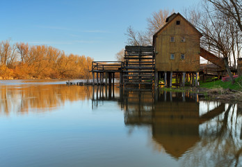 Historic wooden watermill with reflection.