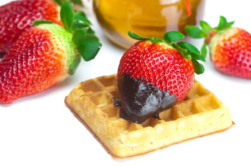 big juicy ripe strawberries in chocolate, a jar of honey and waf