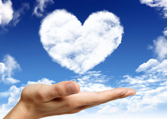 Hand holding heart shape cloud and blue sky