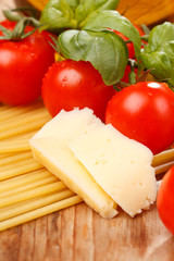 pasta, olive oil and tomatoes on the wood background